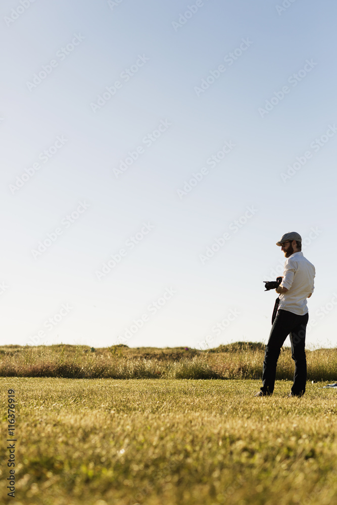 Man with camera standing in grassy field on sunny day Man with camera standing in grassy field on sunny day