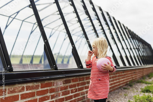 Girl holding ball while standing by glass built structure photo