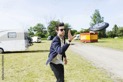 Man in sunglasses throwing plastic disc on grassy field photo