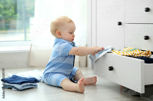 Canvas-taulu Baby throwing up clothes from wooden chest