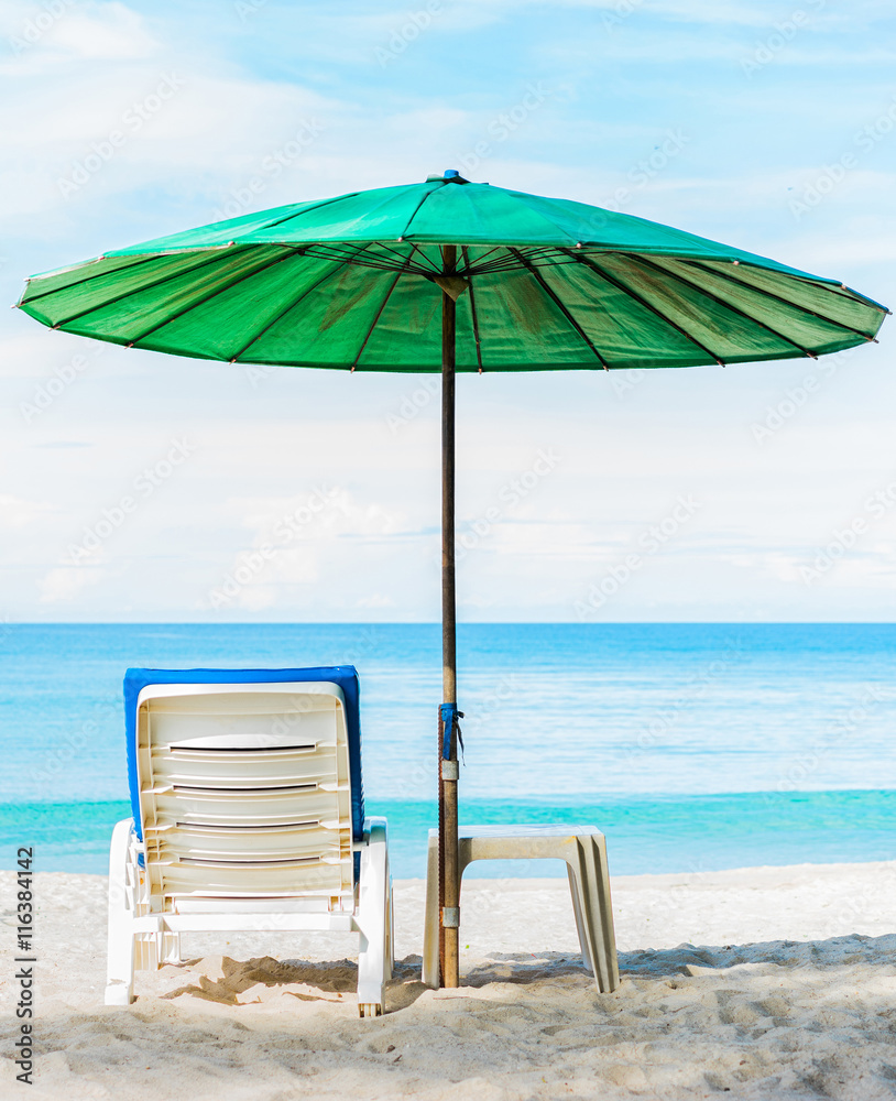 Beach umbrella and chair on the beach. Vertical shot.