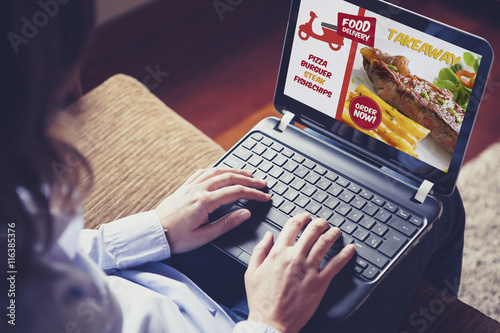 Woman ordering take away food by internet with a laptop while sitting at home.