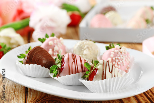 Strawberries covered with different chocolate on white plate
