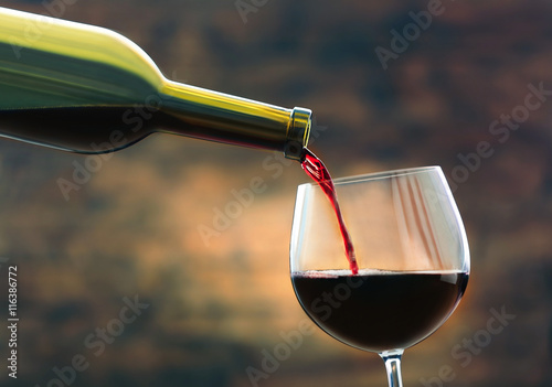 Red wine pouring in glass on brown background