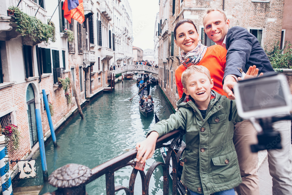 Obraz premium Happy family take a self photo on the bridge over Venecian chann