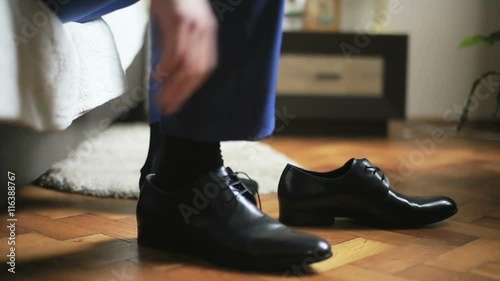 Man dressing black leather shoes with a help of shoehorn preparing for formal event