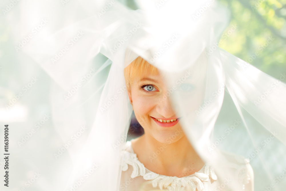 Blue-eyed bride smiles being hidden under a veil Blue-eyed bride smiles being hidden under a veil