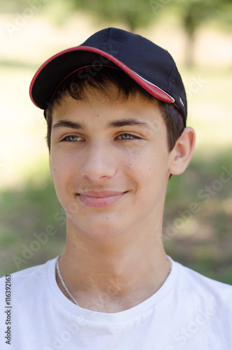 Close up portrait of a cute teenager in a baseball cap. © luckykot