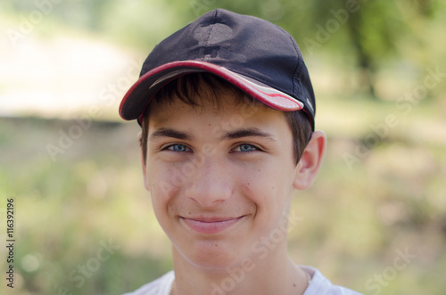 Close up portrait of a cute teenager in a baseball cap. © luckykot