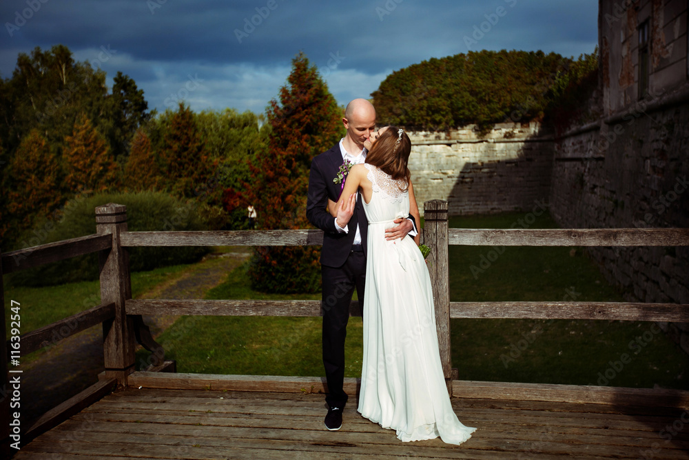 A wedding couple kisses standing behind an old castle