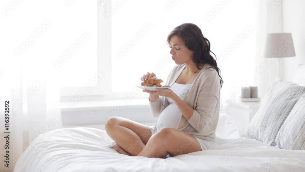 pregnant woman eating croissant in bed at home 25 pregnant woman eating croissant in bed at home 25