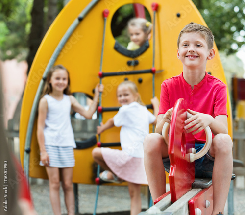 Smiling boy sitting on swing on children's playground