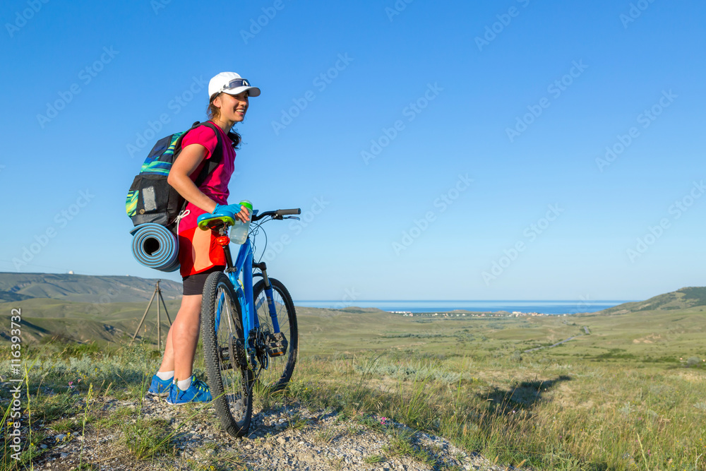 Gril with a bkie standing on the hill.