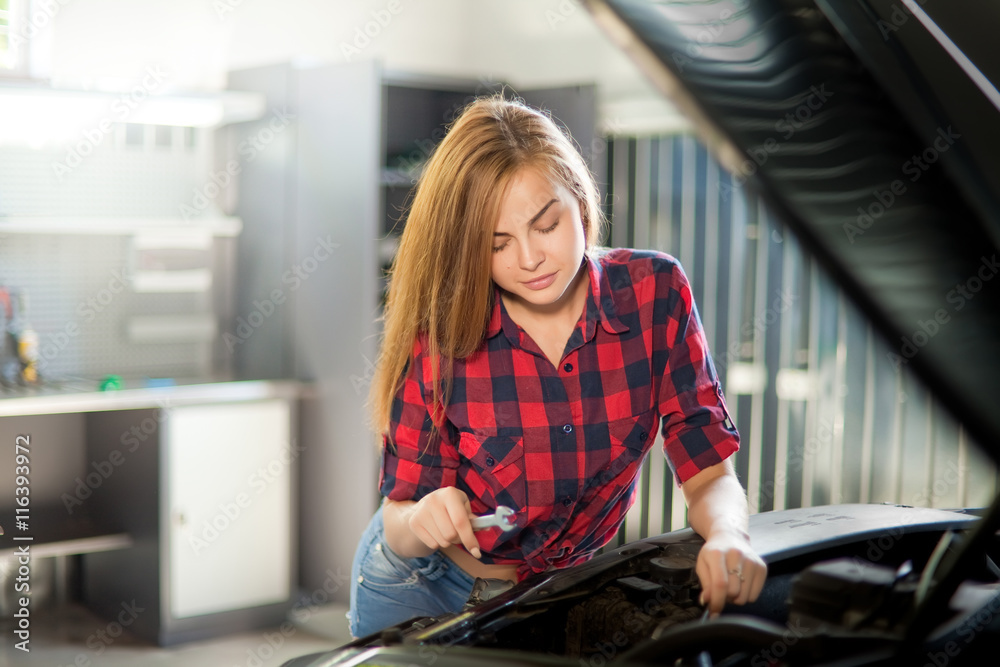 Young sexy brunette mechanic in checked shirt in garage. Young sexy brunette mechanic in checked shirt in garage.