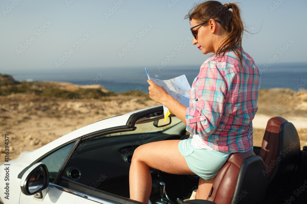 Young pretty woman see the map near the cabriolet