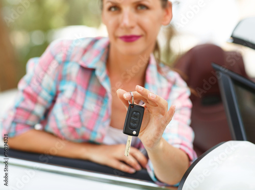 Woman standing near convertible with keys in hand - concept of b