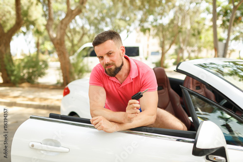 Bearded man standing near convertible with keys in hand
