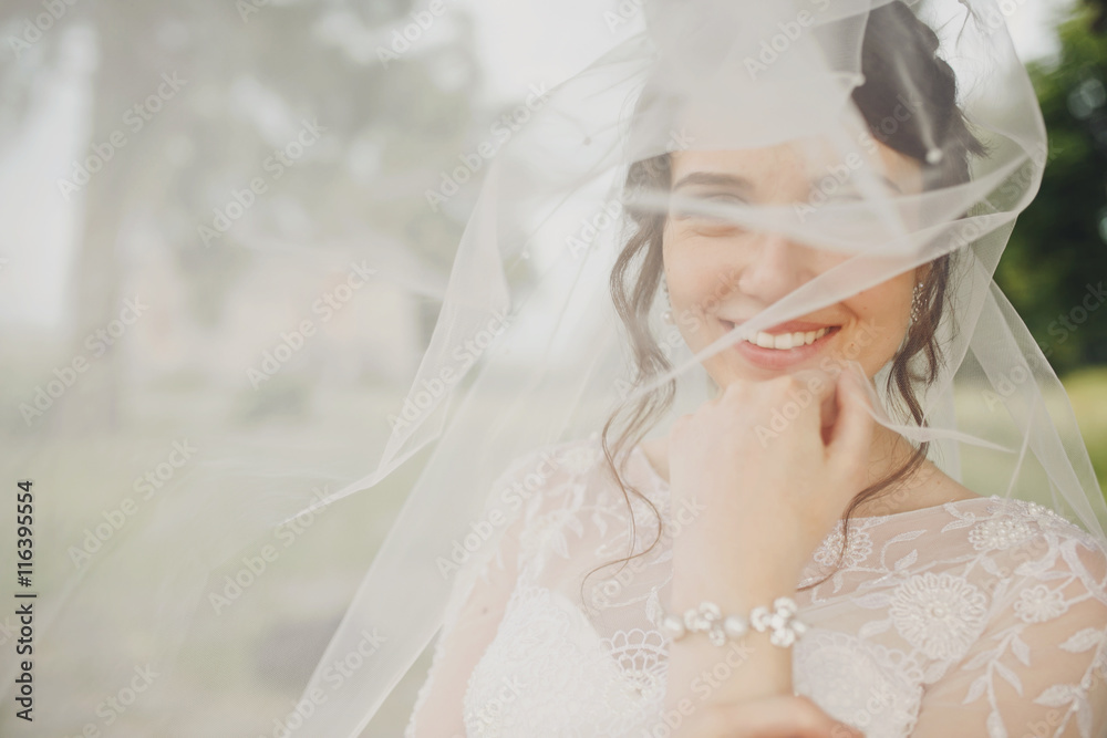 Pretty bride smiles shying under a veil Pretty bride smiles shying under a veil