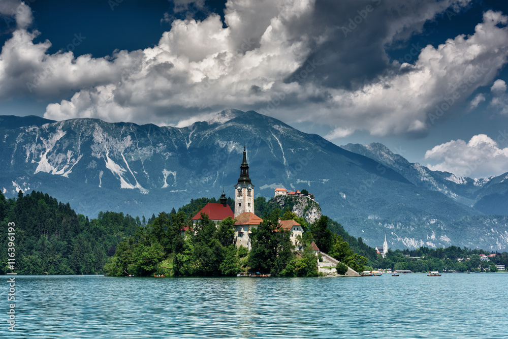 Cloudy day on the alpine lake Bled, view on the island with the church and Julian Alps, Slovenia, Europe