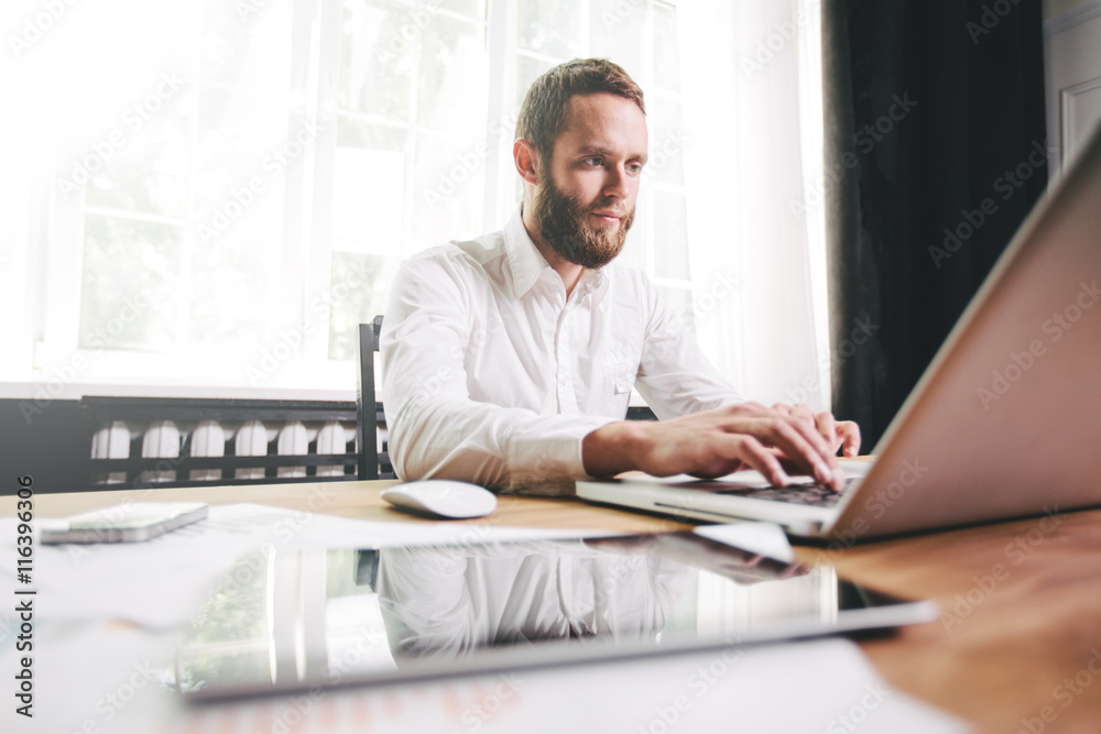 Man working at the office next to a window wearing white shirt