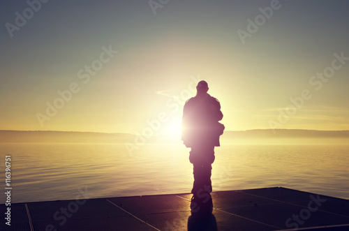 Alter Mann als Silhouette vor der untergehenden Sonne am Bodensee