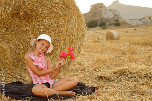 Giovane donna seduta su un campo di fieno photo