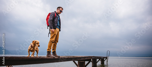 Man and his dog standing on wooden dock