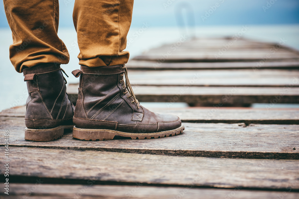 Close up on man standing on dock and wearing leather boots