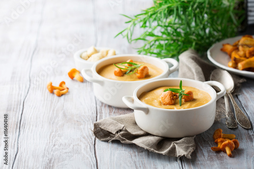 Soup with chanterelles and herbs, whitw wooden background
