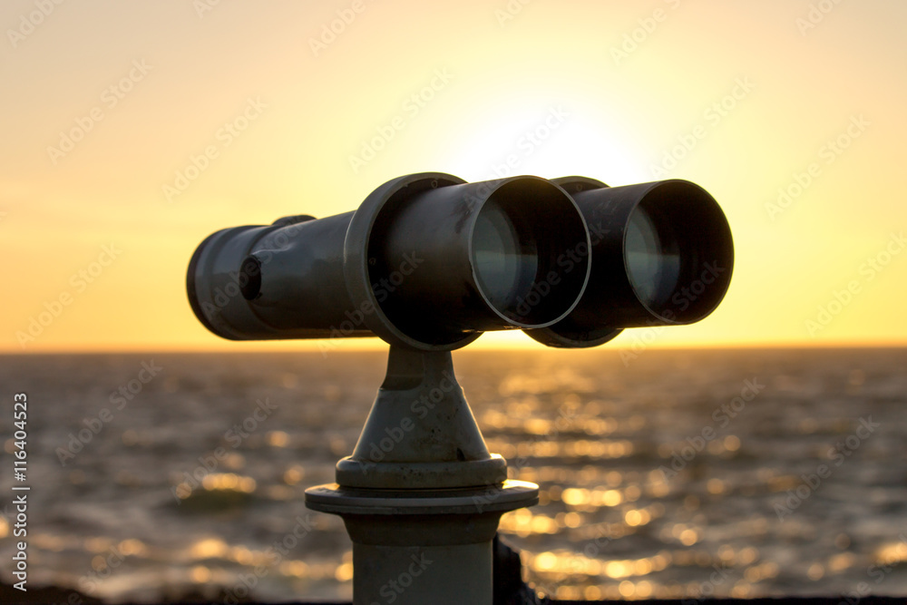 White telescope stands on sea coast in front of golden sunset White telescope stands on sea coast in front of golden sunset