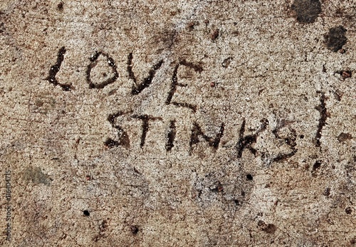 Cynical sentiment scratched into cement, love stinks photo