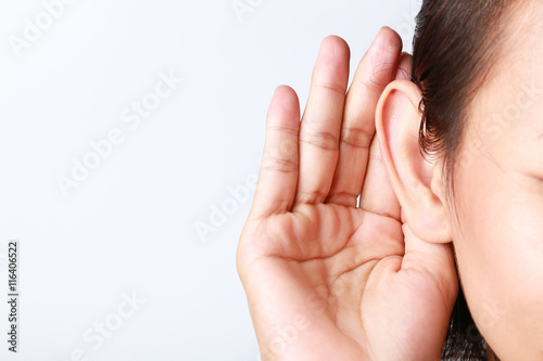 Listening female holds his hand near her ear on white background