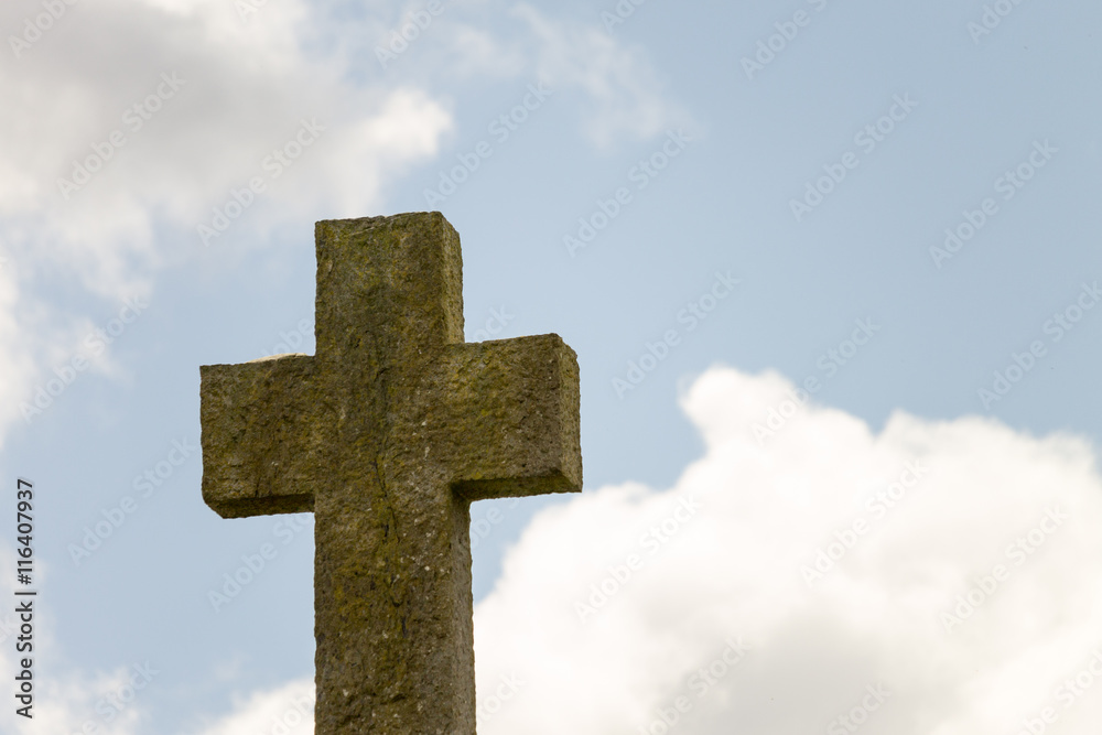 old concrete Cross on a hill with sky and clouds behind it