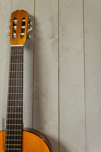 old Spanish guitar resting against wooden slats