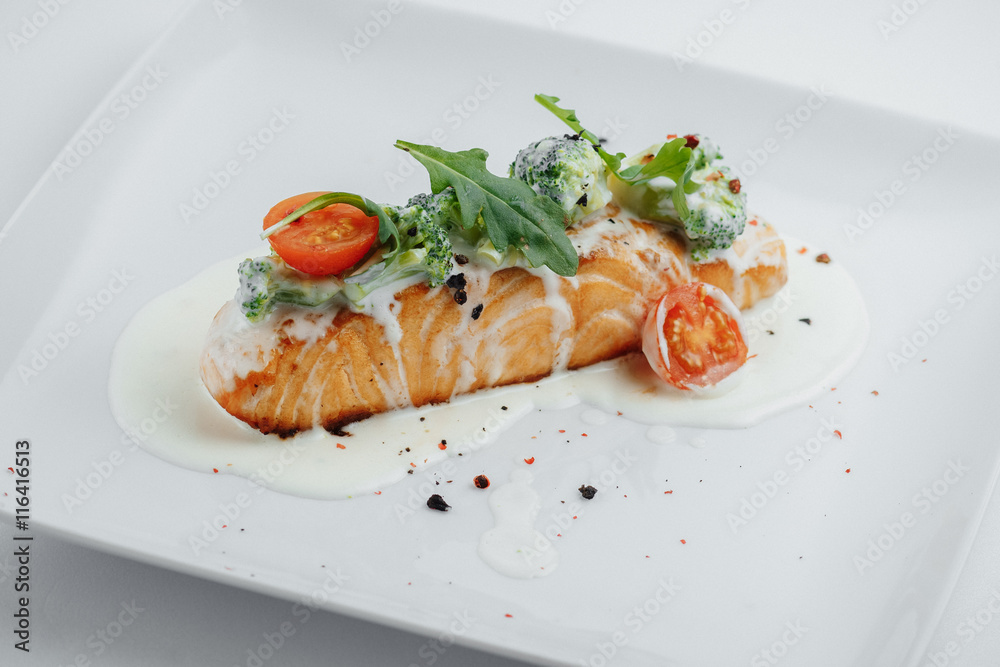 red fish on a white plate with tomato sauce and broccoli red fish on a white plate with tomato sauce and broccoli
