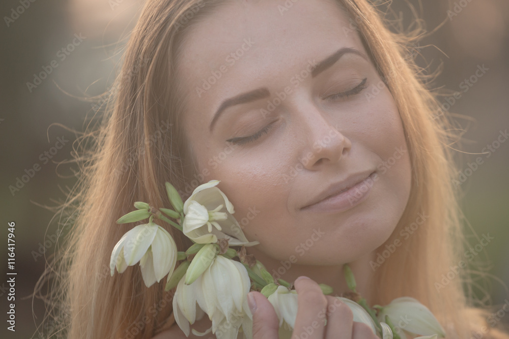 close-up portrait.. Young beautiful pretty woman posing in long dress against in the field with white flowers close-up portrait.. Young beautiful pretty woman posing in long dress against in the field with white flowers