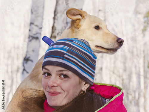 Double portrait of a young girl with a dog in a birch grove in winter.
