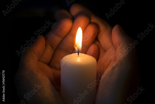 Human hands holding a burning candle