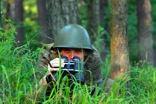 Военный солдат разведчик с биноклем в лесу