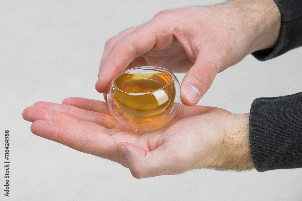 man's hands holding a transparent cup of liquid, green tea man's hands holding a transparent cup of liquid, green tea
