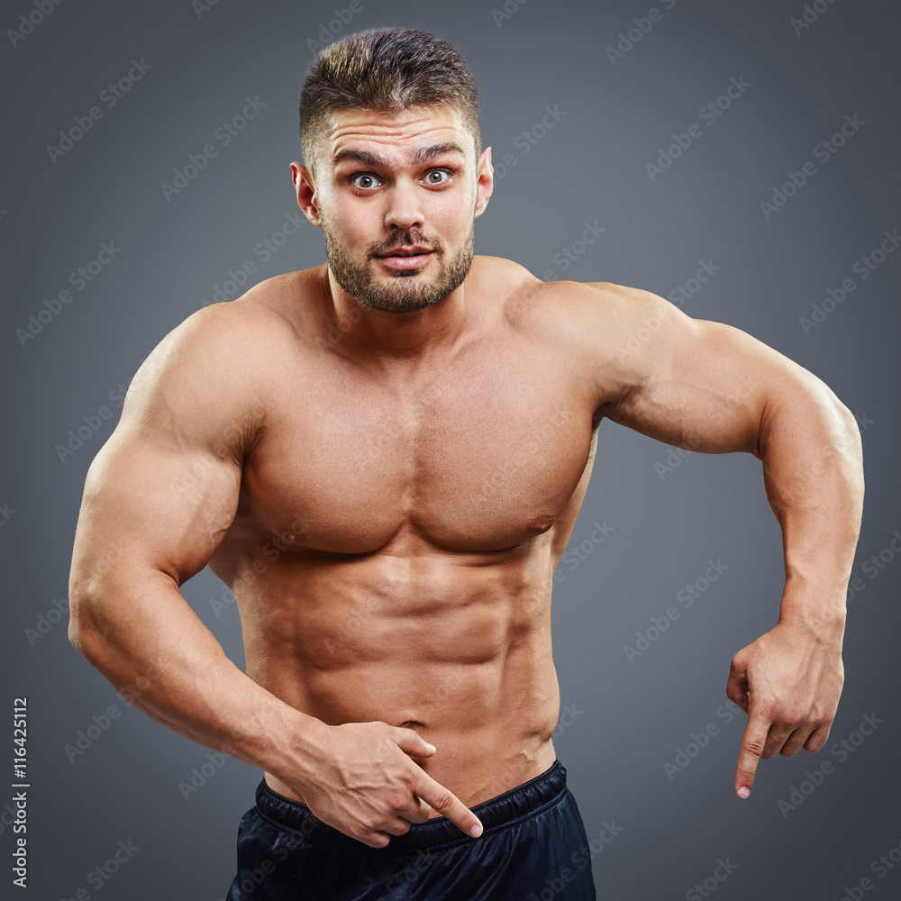 Portrait of muscular man who is pointing a fingers down Portrait of muscular man who is pointing a fingers down