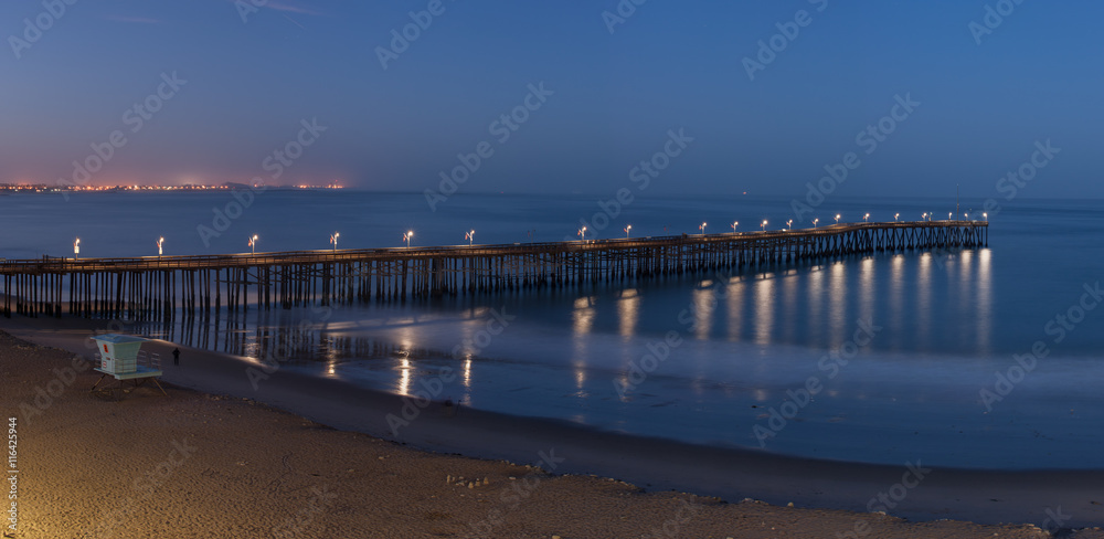 Panoramic view of pier illuminated by lamps at dawn.