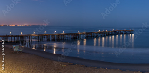 Panoramic view of pier illuminated by lamps at dawn.