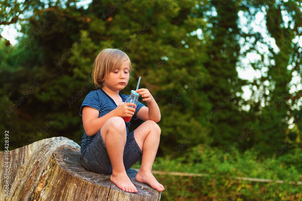 Fototapeta premium Cute little boy drinking smoothie shake outdoors