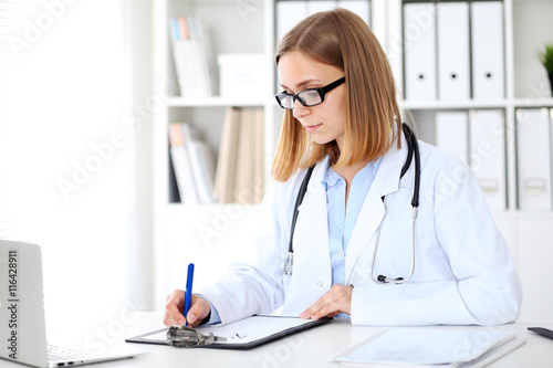 Female doctor writing a medical prescription at clipboard