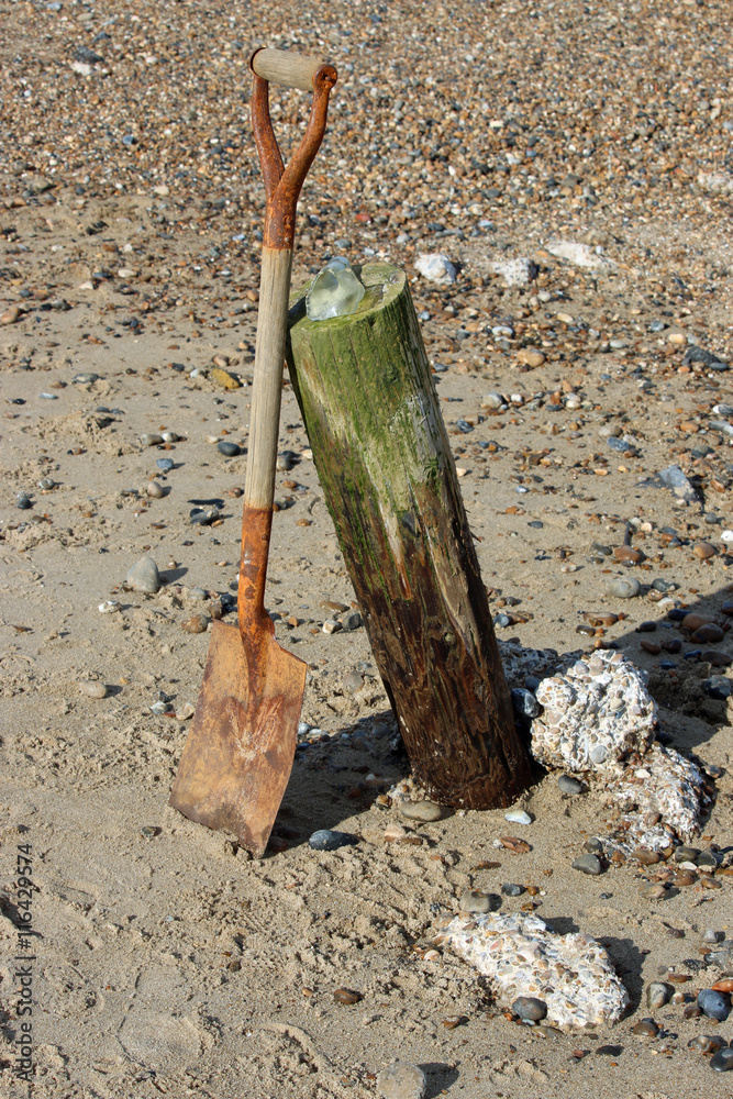 Spade leaning against breakwater on beach Spade leaning against breakwater on beach