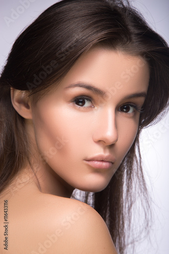 Closeup portrait of beautiful girl with clear healthy skin. Looking at the camera over shoulder. perfect fashion model studio photo