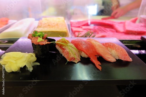 すし屋にて
近くのおすし屋さんです。　まぐろが台の上に。ケースの中にはまぐろ、いか、たまごが見えます。　右奥では板前さんがすしを握っています。 photo
