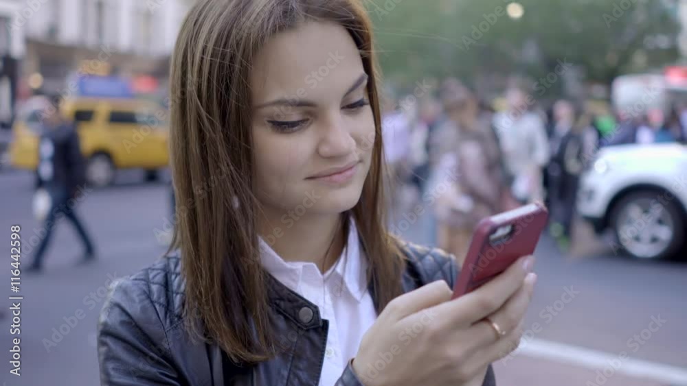 young women walking and texting on smart phone in the city at night young women walking and texting on smart phone in the city at night