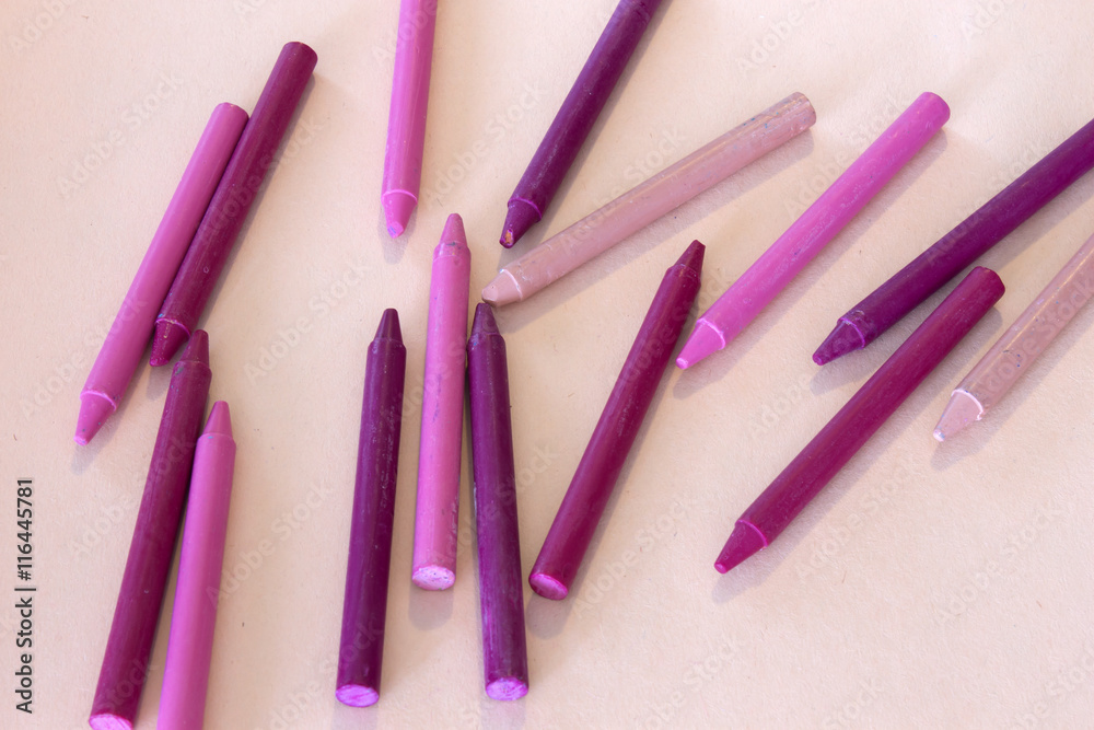 This is a photograph of Pink and Purple crayons on a colorful craft paper background This is a photograph of Pink and Purple crayons on a colorful craft paper background